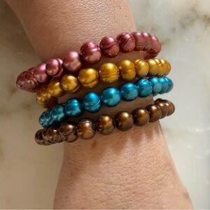 Set of four metallic colored beaded bracelets on stretchable string.